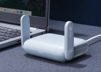 A white Travel Node with two upright antennas next to a laptop.